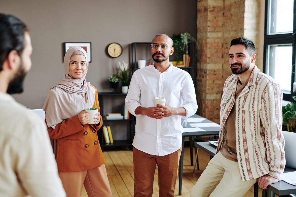 Group of coworkers looking at young Muslim businessman during discussion