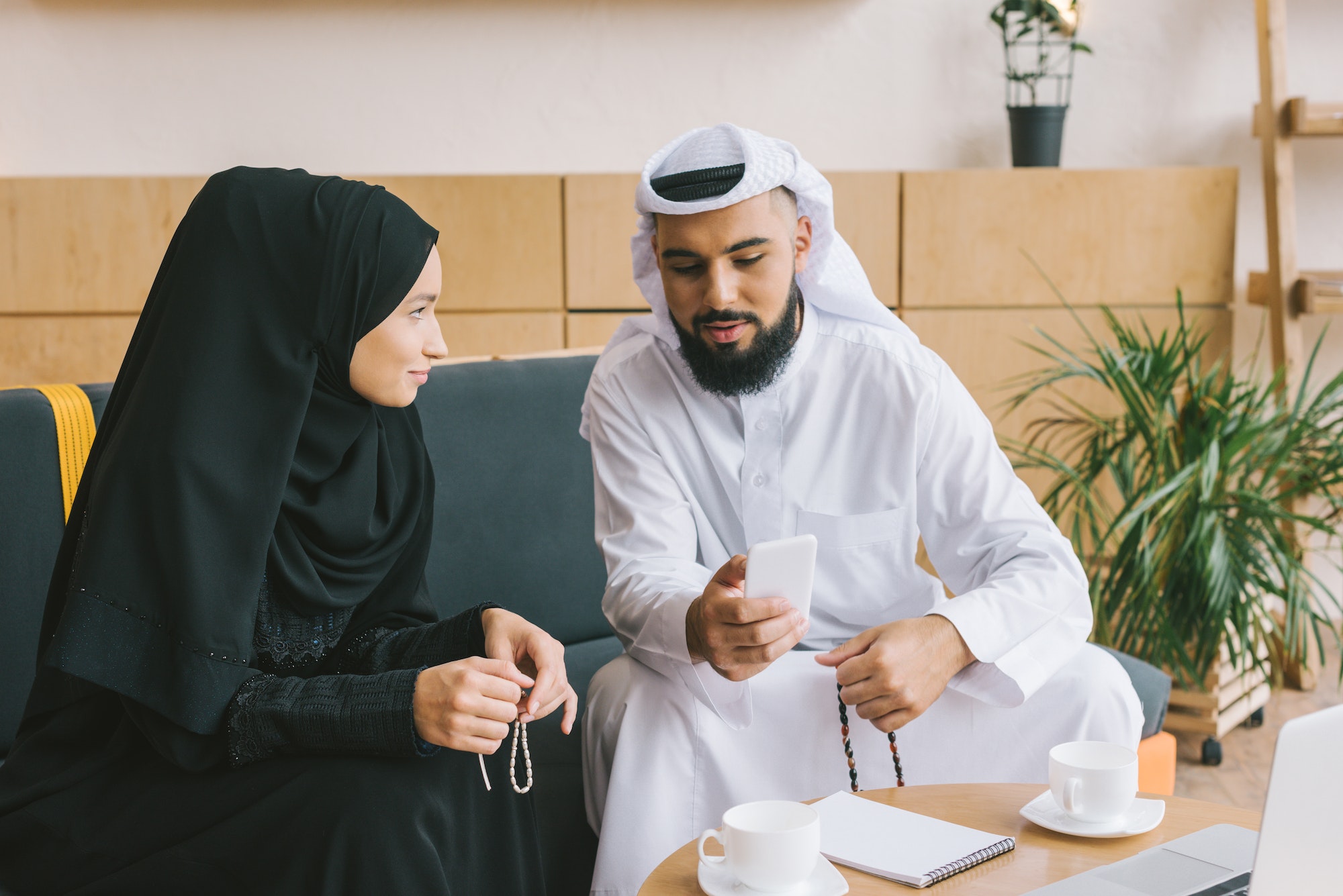 handsome muslim man showing smartphone to woman